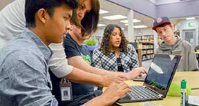 Students collaborating on laptop computer.